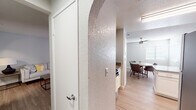This single-floor residence offers a thoughtfully designed layout connecting living, dining, and kitchen areas in a cohesive, open flow. Consistent light wood-style flooring runs throughout the space, complemented by neutral gray and white walls that create a clean, modern aesthetic. Textured ceilings add subtle character across all rooms.

The kitchen is well-equipped with white shaker cabinetry, granite-style countertops, a stainless steel dishwasher, and a double-basin sink. A pass-through window opens toward the dining area, enhancing the sense of connectivity. The dining space accommodates a round table beneath a ceiling fan, with a window providing natural light.

The primary bedroom is generously sized with a walk-in closet and direct access to an en-suite bathroom. The en-suite features a granite-topped vanity with white cabinetry, a soaking tub, and a bright vanity light fixture. The second bedroom is comfortably proportioned with a window and easy access to the second full bathroom, which includes a granite vanity, white cabinetry, and matching finishes consistent with the rest of the home.

Arched interior doorways provide a distinctive architectural detail, adding visual interest throughout the hallways. Natural light filters in through window blinds in each room, contributing to the bright, welcoming ambiance of this well-maintained residence.