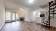 Located in San Marcos, CA, this two-story home offers a clean, modern aesthetic with light wood-style flooring throughout and a bright, neutral color palette. The main floor hosts the open kitchen and living area, two bedrooms, a full bathroom, a closet, and a hallway, providing generous everyday living space. The living room is a standout, featuring a tile-surround fireplace and French doors that invite natural light and outdoor views. A staircase with wood-toned railings leads to the upper floor, where the primary bedroom is situated. This upper-level retreat features a vaulted ceiling with an exposed beam, a large window for natural light, and a sense of privacy and openness. The second bedroom on the main floor includes a windowed nook and a sliding double-door closet. The kitchen is well-appointed with warm wood cabinetry, granite countertops, a double sink, and black appliances including a gas range, dishwasher, and refrigerator. The full bathroom features a granite-topped vanity with a rich wood cabinet, a large mirror, and a full shower-tub combo. The upstairs hallway connects the primary bedroom to the staircase landing, completing this well-organized and thoughtfully designed home.