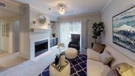 This single-floor residence offers a thoughtfully designed layout that balances comfort and functionality across its key living spaces. The living room serves as the heart of the home, anchored by a tiled fireplace with a classic white mantel and built-in shelving. Crown molding adds architectural detail throughout, while a sliding glass door fills the room with natural light and provides outdoor access. Soft carpeting and neutral grey walls create a warm, cohesive ambiance.

The kitchen is efficiently arranged with rich dark cabinetry, stainless steel appliances including a refrigerator and dishwasher, light countertops, and a distinctive teal subway tile backsplash. Wood-look vinyl flooring runs through the kitchen and bathroom areas, offering both style and durability.

The dining area is a defined, intimate space framed by crown molding and a chair rail, providing a quiet setting for meals. Two well-proportioned bedrooms each feature plush carpet, crown molding, and windows with blinds that allow natural light. One bedroom includes access to a walk-in closet with shelving. The full bathroom offers a dark vanity with white countertop, a tub-shower combination, and coordinating wood-look flooring, completing this cohesive and practical residence.