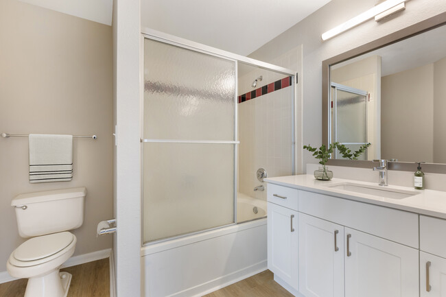 Renovated Package I bath with white speckled quartz countertop, white cabinetry, and hard surface flooring - Avalon Addison