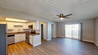 This single-floor residence is designed with a practical, open-concept layout that connects the living area and kitchen into one cohesive space. The living area is generously sized, featuring wood-look plank flooring, neutral gray walls, a textured ceiling, and a ceiling fan with integrated lighting. A sliding glass door fills the space with natural light and provides outdoor access. Adjacent to the living area, the kitchen is well-appointed with white shaker-style cabinetry, subway tile backsplash, dark countertops, and a full suite of stainless steel appliances including a refrigerator, electric range, built-in microwave, and dishwasher. A raised peninsula counter serves as a visual and functional divider between the two spaces.

The bedrooms continue the wood-look flooring and neutral palette, each equipped with a ceiling fan and sliding or hinged closets offering organized storage. Natural light enters through windows fitted with blinds. Two bathrooms serve the unit — one featuring a full tub-shower combination, the other a standalone walk-in shower — both finished with wood-look flooring and clean white fixtures. A walk-in closet provides additional storage elsewhere in the unit.