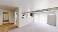 This single-floor residence offers a clean, functional layout designed for comfortable everyday living. The open-concept living area is finished with plush wall-to-wall carpeting and anchored by a large sliding glass door fitted with vertical blinds, flooding the space with natural light and providing views of the greenery outside. Recessed lighting overhead adds a modern touch to the living space.

The kitchen is positioned at the heart of the home, featuring a peninsula-style breakfast bar that connects it to the living area. It is outfitted with two-tone wood cabinetry in a warm, contemporary finish, stone-look countertops, a stainless steel sink, and built-in appliances including a microwave. A window above the sink brings in additional natural light. The kitchen transitions to adjacent areas via wood-look flooring.

The bedrooms are generously proportioned, each carpeted and illuminated by natural light through windows with vertical blinds. The rooms offer a neutral color palette and ample wall space, making them highly adaptable.

The bathroom is thoughtfully finished with large-format stone tile flooring, a dark wood vanity with a white countertop, and a full tub-shower combination featuring white tile surround and brushed bronze fixtures. The overall design of the space is clean, bright, and move-in ready.
