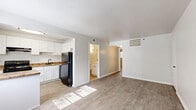 Located at 411 York St in Williamsburg, Virginia, this single-floor unit offers a thoughtfully arranged layout across two bedrooms, two bathrooms, a combined kitchen and living area, and a connecting hallway. The interior presents a clean, neutral palette throughout, with light gray walls and white trim creating a bright, cohesive aesthetic.

The living area features wood-look luxury vinyl flooring and a front entry door, providing a welcoming open feel. Adjacent to the living space, the kitchen is well-equipped with white shaker-style cabinetry, granite-tone countertops, stainless steel appliances including a refrigerator and range, an under-cabinet exhaust hood, and a sink. Two windows allow natural light to fill the kitchen, offering views of surrounding greenery.

The primary bedroom features plush carpeting and a double-door closet, while the second bedroom also offers carpeted floors, a ceiling fan, a window, and ample wall space. Both bathrooms are finished with warm travertine-style tile flooring, white vanities with dark hardware, large mirrors, and wall sconces. One bathroom includes a full tub-shower combination, while the other features a single vanity with toilet.

Overall, the unit maintains a clean, move-in-ready presentation with consistent finishes throughout.