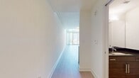 This two-story residence offers a spacious 1040 square feet of living area, efficiently distributed across two levels. The ground floor encompasses 490 square feet, while the upper level provides an additional 560 square feet. The property features a total of five rooms, allowing for versatile living arrangements.

A notable architectural element is the loft-style upper level, partially visible in the image. White railings along the edge of the upper floor create an open, airy feel and allow for visual connection between the two levels. This design choice enhances the sense of space and light throughout the home.

The interior showcases a minimalist aesthetic with clean, white walls that brighten the space and provide a blank canvas for personalization. Light-colored laminate flooring runs throughout, contributing to the overall bright and modern ambiance. The flooring's neutral tone complements the white walls, creating a cohesive and contemporary look.

The image reveals electrical outlets along the baseboard, indicating modern wiring throughout the property. While specific room functions are not detailed, the open layout and generous square footage suggest potential for comfortable living spaces, including areas for relaxation, dining, and work.