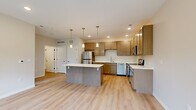 Located at 1915 S Mattis Ave in Champaign, IL, this one-bedroom, one-bathroom unit offers a thoughtfully designed layout that maximizes every square foot of living space. The open-concept kitchen and living area serves as the heart of the unit, anchored by a central kitchen island with a clean white countertop that provides both prep space and a casual dining area. Warm-toned cabinetry lines the kitchen walls, complemented by stainless steel appliances including a refrigerator, microwave, dishwasher, and range. Pendant lighting hangs above the island, adding a modern touch, while recessed lighting throughout ensures the space remains bright and welcoming. Light wood-style flooring flows seamlessly across the main living area, enhancing the open and airy feel. The living area benefits from natural light through a well-positioned window. The bedroom is a comfortable retreat finished with plush carpeting, a closet, and a window overlooking greenery, bringing in natural light and outdoor views. The bathroom features a wood-toned vanity, light flooring, and clean, neutral finishes. Throughout the unit, a consistent neutral color palette and modern design details create a cohesive and functional living environment.