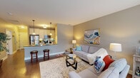 Located at 3181 Charlevoix Dr SE in Grand Rapids, Michigan, this single-floor unit offers a well-designed layout that balances functionality with a warm, inviting aesthetic. The open-concept living and kitchen area forms the heart of the space, where rich hardwood-style flooring flows seamlessly throughout. The living room features neutral gray walls, a generous seating area, and ambient lighting that creates a relaxed atmosphere.

The kitchen is efficiently designed with crisp white cabinetry extending to the ceiling for ample storage, a subway tile backsplash, and a full suite of stainless steel appliances including a gas range, over-the-range microwave, and refrigerator. A raised breakfast bar with seating connects the kitchen to the living area, reinforcing the open feel.

The bedroom is carpeted for comfort and receives natural light through a pair of windows dressed with sheer curtains. A door leads to a dedicated walk-in closet, providing practical storage. The full bathroom features wood-look flooring, a vanity with classic cabinetry, and a shower-tub combination, finished in a clean, neutral palette. Overall, the space presents a cohesive, move-in-ready environment with thoughtful details throughout.