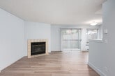 This single-floor unit offers a well-organized layout with a comfortable and functional living environment. The living area is a standout space, anchored by a tile-surround fireplace that serves as a focal point, complemented by light wood-style flooring and textured ceilings. Vertical blinds frame a sliding glass door that opens to a view of a private outdoor area, allowing natural light to fill the room. A baseboard heating system runs along the walls, ensuring warmth throughout. The kitchen is thoughtfully designed with white cabinetry, granite-style countertops, a stainless steel range with overhead ventilation, and a pass-through counter that connects it to the living and dining areas, creating an open and airy feel. Light wood flooring continues through the kitchen and into the hallway, which leads to the additional rooms. The bedroom is a quiet, well-proportioned room with a window overlooking a green outdoor setting and its own baseboard heater. The bathroom features a full-size soaking tub and shower combination with clean white surround walls and tile flooring. Throughout the space, a neutral grey and white color palette creates a cohesive, modern aesthetic.