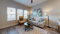 Located at 144 E 62nd St in Savannah, Georgia, this single-story residence offers a thoughtfully designed layout with modern finishes throughout. The open floor plan, visible in the overhead 3D scan, connects the living areas, kitchen, and bedrooms in a cohesive and functional arrangement.

The living room serves as the heart of the home, featuring durable wood-look flooring, neutral gray walls, and a bank of double-hung windows that flood the space with natural light and offer views of the surrounding landscape. A ceiling fan adds practicality overhead.

The kitchen is well-equipped with white shaker-style cabinetry, speckled granite countertops, and a full suite of stainless steel appliances, including a range, microwave, and refrigerator. A soft blue subway tile backsplash adds a subtle pop of color against the clean white cabinetry, while wood-look flooring continues throughout.

The bedrooms feature plush carpeting, neutral walls, and ample natural light from double windows. One bedroom includes a wall-mounted mini-split HVAC unit, ensuring individualized climate control. Both rooms offer generous space for furnishings.

The bathroom is finished with a white vanity, granite countertop, brushed gold fixtures, a large mirror, and wood-look flooring, creating a clean and polished aesthetic throughout.