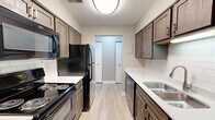 Located at 4256 Oak Forest Ct SE in Kentwood, Michigan, this single-floor, 2-bedroom, 1-bathroom residence offers a practical and well-organized layout across its six distinct spaces, including a living room, kitchen, two bedrooms, bathroom, entrance, and hallway.

The galley-style kitchen is a standout feature, outfitted with rich dark wood cabinetry, white quartz-style countertops, a classic subway tile backsplash, and black appliances including a range, microwave, refrigerator, and dishwasher. Light wood-style flooring runs throughout the kitchen, lending a clean, modern feel.

The living room is generously sized for the footprint of the home, featuring plush neutral carpeting and a full sliding glass door dressed with vertical blinds, allowing natural light to filter in and providing access to the outdoors. The bedrooms are carpeted as well; the primary bedroom is notably spacious and includes two closet doors, while the secondary bedroom features light hardwood-style flooring, a ceiling fan, and a window with natural light. The full bathroom is neatly appointed with a wood-toned vanity, white quartz countertop, tiled tub-shower combo, and wood-style flooring, maintaining a cohesive and updated aesthetic throughout the home.