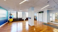Located at 111 Cooper Street in Ottawa's Centretown neighbourhood, this fitness facility offers a thoughtfully designed, single-floor layout that accommodates a wide range of exercise activities. The space is divided into two distinct zones, each tailored to a specific workout experience.

The exercise studio features warm hardwood flooring, structural white columns, and large windows that invite natural light throughout. A vivid teal accent wall and a serene ocean-themed mural add visual character to the open, airy environment. Frosted glass partitions provide semi-private areas within the studio, while a wall-mounted barre and yoga mats suggest the space is well-suited for group fitness classes, yoga, and movement training.

The dedicated gym area presents a striking visual identity, with bold orange and white chevron-patterned walls set against a checkered tile floor. The room is generously equipped with Life Fitness treadmills, elliptical machines, a cable and weight machine, a Smith machine, a dumbbell rack, and various strength-training benches. Full-length mirrors and linear LED lighting throughout enhance visibility and create an energetic atmosphere. Together, both areas form a comprehensive, professionally appointed fitness centre ideal for diverse training needs.