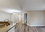 Located at 9873 Lawrence Rd in Boynton Beach, Florida, this single-floor residence offers a well-planned open layout with warm neutral tones and a clean, updated aesthetic throughout. The living area features wood-look plank flooring and vaulted ceiling details, with a ceiling fan overhead and a large sliding glass door that floods the space with natural light and provides views of the surrounding greenery. A decorative chandelier adds a touch of elegance to the dining area, which flows seamlessly from the main living space. The kitchen is thoughtfully designed with white shaker-style cabinetry, a classic subway tile backsplash, dark quartz countertops, stainless steel appliances including a refrigerator, electric range, and built-in microwave, and a peninsula with an undermount sink that opens toward the living and dining areas — ideal for everyday functionality and entertaining. The bedrooms are carpeted for comfort and feature natural light from windows with outdoor views, along with generous closet space. The bathroom is finished with clean white tile surrounding a tub-shower combination and gold-toned fixtures, maintaining a consistent, cohesive design palette. Overall, this residence presents a bright, neutral, and move-in-ready environment in a well-located South Florida community.