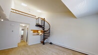Located at 1202 Crescent Dr in Tarrytown, NY, this two-floor residence offers a thoughtfully designed layout with a blend of functional and architectural character. The main living area immediately impresses with soaring vaulted ceilings and skylights that flood the space with natural light, creating an open and airy atmosphere. A dramatic wrought-iron spiral staircase with wooden treads and handrails serves as a striking centerpiece, connecting the two floors with elegance and efficiency.

The entry foyer features vaulted ceilings, a coat closet, and track lighting, setting a welcoming tone. The kitchen is equipped with warm oak cabinetry, granite-style countertops, tile flooring, and white appliances including a range, dishwasher, and refrigerator. The bedrooms are generously sized, carpeted, and filled with natural light from large windows offering leafy outdoor views, with wall AC units and baseboard heating ensuring year-round comfort. Multiple closets with built-in shelving provide ample storage throughout.

A clean, simply appointed bathroom includes an oak vanity, mirror, and tile flooring. Neutral tones, wall-to-wall carpeting in the living spaces, and an overall understated aesthetic make this a versatile and comfortable residence in the charming village of Tarrytown.