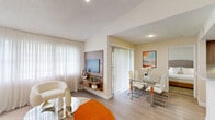 Located in the Kendale Lakes area of Miami, FL, this 2-bedroom, 2-bathroom residence offers a functional and comfortable single-floor layout. The open-concept living and dining area is bright and welcoming, featuring light wood-style flooring, large sheer-draped windows that invite abundant natural light, and a wall-mounted media unit with built-in shelving. Vertical blinds lead to an outdoor access point, enhancing the connection to the exterior. The galley-style kitchen is efficiently designed with warm wood-toned cabinetry, light quartz countertops, a stainless steel sink, and a full suite of appliances including an electric range and refrigerator. The primary bedroom is a comfortable retreat with plush carpeting, a walk-in closet featuring wire shelving, and direct access to a private bathroom. The second bedroom also features carpet flooring and a window with greenery views, providing a serene atmosphere. Both bathrooms are similarly appointed with tub-shower combinations, wood-toned vanity cabinetry, quartz countertops, and large mirrors. A hallway connects the main rooms, with two closets offering practical storage solutions throughout the residence.