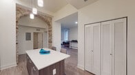Located in the heart of downtown Wilmington, Delaware, this thoughtfully designed single-floor residence seamlessly blends modern aesthetics with historic character. Exposed brick archways and columns serve as dramatic focal points throughout the space, contrasting beautifully against crisp white walls and wood-look plank flooring.

The open-concept kitchen is a standout, featuring high-gloss upper cabinetry, wood-toned lower cabinets, a classic subway tile backsplash, stainless steel appliances, and a spacious quartz-topped island with pendant lighting overhead. The kitchen flows naturally into the dining area, where large windows invite an abundance of natural light and provide views of the surrounding cityscape.

The living area offers generous proportions, with an open layout ideal for both relaxing and entertaining. Two well-appointed bedrooms each feature tall windows overlooking the urban streetscape, ample closet space with louvered bifold doors, and warm wood-look flooring.

The bathrooms are finished to a high standard, with large-format marble-look tile flooring throughout. The primary bathroom showcases an arched exposed brick surround framing a clean white vanity, while the secondary bathroom includes a full tub and shower with elegant tile work. This residence offers an exceptional combination of historic charm and modern convenience in a prime downtown location.