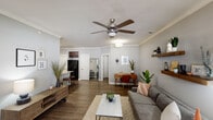 This single-floor residence offers a cohesive, modern design throughout its thoughtfully arranged layout. The living room serves as the central gathering space, featuring crown molding, dark hardwood-style flooring, and a ceiling fan with light fixture. Neutral gray walls create a calm backdrop, while floating wood shelves add functional character. A front-facing window brings in natural light, and the open layout provides a clear sightline through to the kitchen area.

The kitchen is well-equipped with rich dark cabinetry, light granite countertops, a subway tile backsplash, and black appliances. A peninsula with seating for three bar stools connects the kitchen to the living space, making it ideal for casual dining or entertaining.

The bedroom is a quiet retreat with plush carpet, crown molding, and a skylight that introduces additional natural light. It includes a walk-in closet and direct access to an en-suite bathroom, which features a large sliding-glass shower enclosure with floor-to-ceiling tile and mosaic accent detailing.

Together, the spaces reflect a consistent mid-century modern aesthetic, with warm wood tones, clean lines, and carefully selected finishes that lend a polished yet comfortable character throughout.