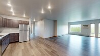 This well-appointed 3-bedroom, 2-bathroom residence on First Ave N in Fargo, ND offers a thoughtfully designed single-floor layout with generous living space throughout. The open-concept living room is bright and airy, featuring large windows that frame views of lush trees and the city skyline, light gray luxury vinyl plank flooring, and baseboard heating. The kitchen is a standout, equipped with rich dark wood cabinetry, stainless steel appliances including a range, microwave, dishwasher, and refrigerator, recessed lighting, and warm hardwood-style flooring. The spacious primary bedroom offers large windows with outdoor views and ample room for furnishings. All three bedrooms feature light-toned LVP flooring and natural wood door trim, lending a clean, modern aesthetic. The two bathrooms are well-finished — one includes a walk-in shower with a white surround, while the other features a full tub-shower combo. Closets throughout are outfitted with wire shelving systems for organized storage. A dedicated in-unit laundry room houses a full-size side-by-side washer and dryer with overhead wire shelving, adding everyday convenience to this functional and attractive home.
