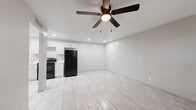 This 2-bedroom, 1-bathroom single-story residence offers a clean, modern aesthetic with consistent light-toned tile flooring running throughout every room, creating a cohesive and easy-to-maintain interior. The open-concept living area is bright and airy, with recessed lighting and a ceiling fan providing both illumination and comfort. Large front-facing windows allow natural light to fill the space while offering views of the surrounding greenery outside.

The kitchen is efficiently designed with crisp white shaker-style cabinetry, marble-look countertops, a stainless steel sink, and black appliances including an electric range and refrigerator. Ample upper and lower cabinet storage makes this a highly functional cooking space.

Both bedrooms are comfortably sized, with the primary bedroom offering generous square footage, a ceiling fan, and a dedicated closet. The secondary bedroom features a bright window with an outdoor view, adding a sense of openness to the room.

The full bathroom is thoughtfully finished with large-format gray tile on the walls and floor, a soaking tub with a built-in shower niche, brushed nickel fixtures, and a white vanity topped with a marble-look countertop. A hallway connects the living areas to the private rooms, keeping the layout organized and functional. Overall, the space presents a fresh, move-in-ready environment with modern upgrades throughout.