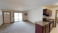 This single-floor unit offers a practical and comfortable layout designed for everyday living. The open-concept living area is carpeted and filled with natural light from a large sliding glass patio door, which also provides outdoor access. A wall-mounted air conditioning unit and baseboard heating ensure year-round climate comfort. A ceiling fan is present in the main living space, contributing to airflow and ambiance.

The kitchen is positioned adjacent to the living area and features rich, dark-toned cabinetry, stone-patterned laminate countertops, a double stainless steel sink, and black appliances including a refrigerator and dishwasher. The tile flooring in the kitchen offers a clean contrast to the carpeted living spaces. A peninsula counter connects the kitchen to the living area, providing additional prep space and an open sightline.

The bedrooms are carpeted and well-proportioned, each equipped with ceiling fans and windows fitted with vertical blinds that allow natural light while maintaining privacy. Baseboard heating is present in each room.

Two bathrooms serve the unit — one featuring a tub and shower combination, and the other equipped with a sliding glass-door shower enclosure. Both bathrooms maintain a clean, neutral palette throughout.