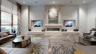 Located at 1905 Concord Blvd in Concord, California, this single-floor space offers a generously sized, open-plan layout that seamlessly integrates a living room and dining area within a contemporary, upscale interior. The design is defined by soaring ceilings that amplify the sense of openness, while wood-look plank flooring in warm neutral tones runs throughout, providing visual continuity across all zones.

The living area serves as the focal point of the space, anchored by a striking floor-to-ceiling tile-clad fireplace wall flanked by two wall-mounted televisions set into recessed niches. Curved sectional seating and layered area rugs contribute to an inviting, lounge-like atmosphere. Large floor-to-ceiling windows dressed with patterned drapery flood the space with natural light and offer views to an outdoor courtyard. Ceiling fans maintain comfort throughout.

A raised billiards area with a chandelier adds a recreational dimension, partially separated from the main lounge by a subtle level change. Decorative columns with geometric detailing define zones within the open floor plan without obstructing sightlines.

The dining area features a round table with mixed upholstered seating, flanked by curated artwork and a decorative wood cabinet set within a tiled niche. Throughout, the space maintains a cohesive, modern aesthetic through a neutral palette, carefully selected furnishings, and thoughtfully placed art.