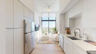 Located at 303 S Federal Hwy in Hollywood, Florida, this modern one-bedroom, one-bathroom residence offers a thoughtfully designed open-concept layout that maximizes every inch of its intimate footprint. Light hardwood flooring flows throughout, complementing a crisp, all-white palette that creates a bright and airy ambiance.

The kitchen, dining, and living areas flow seamlessly into one another, anchored by a sleek galley-style kitchen outfitted with flat-front cabinetry extending to the ceiling, stainless steel appliances including a full-size refrigerator, dishwasher, range, and microwave, as well as a undermount sink with modern fixtures and clean quartz-style countertops. A ceiling fan overhead adds comfort to the open living space, which is bathed in abundant natural light from dramatic floor-to-ceiling windows that lead directly to a private balcony. From the balcony, sweeping elevated views of the Hollywood cityscape and a glimpse of the Atlantic Ocean provide a stunning backdrop.

The bedroom is generously proportioned with large windows that frame beautiful sky and city views, filling the room with natural light. Two closets offer ample storage. The bathroom features light wood-style flooring, a glass-enclosed walk-in shower with hexagonal tile flooring, and clean white walls. A dedicated laundry area completes this well-appointed residence.