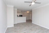 Located at 5750 Buffington Rd in Union City, Georgia, this single-floor residence offers a well-designed layout with a cohesive, neutral color palette that creates a bright and welcoming atmosphere throughout. The living area is an open, airy space highlighted by light hardwood-style flooring, crown molding, and a ceiling fan, with multiple windows fitted with blinds that invite natural light and offer views of the surrounding greenery and neighborhood. An elegant arched doorway connects the living area to the entryway, adding a refined architectural detail to the interior. The kitchen features a galley-style layout with white cabinetry, a double stainless steel sink, ample counter space, and black stainless appliances including a range and refrigerator, all set on matching hardwood-style flooring. The bedroom is carpeted for comfort and includes a generously sized window with outdoor views. The bathroom is appointed with white cabinetry, a single vanity with a large mirror, well-lit overhead lighting, and hardwood-style flooring, offering a clean and functional space. Louvered closet doors, six-panel interior doors, and consistent trim details throughout reflect a thoughtful and cohesive design approach.