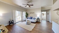 This well-appointed one-bedroom, one-bathroom residence in Chandler, Arizona offers a thoughtfully designed layout across a single floor. Rich wood-style flooring flows throughout, complementing the warm, neutral palette that gives the home a bright and cohesive feel.

The open-concept living and kitchen area serves as the heart of the home. The living room features crown molding, a ceiling fan, and sliding glass doors that open to a private patio, allowing natural light to fill the space. The kitchen is equipped with white shaker-style cabinetry, granite countertops, a peninsula with an integrated sink, stainless steel appliances, and a tasteful tile backsplash — a functional and stylish setup for everyday living.

The bedroom is a comfortable retreat with a generously sized window overlooking lush greenery, offering a peaceful outdoor view and ample natural light. A dedicated closet with built-in shelving provides practical storage.

The bathroom includes a single vanity with a light countertop, a full tub-shower combination, and wood-style flooring that maintains design continuity. A separate in-unit laundry area with overhead shelving adds everyday convenience. A hallway connects the spaces efficiently, completing a compact yet complete and functional floor plan.
