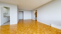 Located at 299 Glenlake Ave in Toronto's Junction neighbourhood, this one-bedroom, one-bathroom unit offers a well-organized layout across a single floor. Classic parquet wood flooring runs throughout the living areas and bedroom, adding warmth and character to the space.

The bright living room is a standout feature, showcasing a full wall of floor-to-ceiling sliding glass doors that open onto a private balcony. The expansive glazing floods the room with natural light and frames sweeping views of the surrounding Toronto skyline and treetops.

The kitchen is positioned centrally and features white cabinetry with sleek bar-style hardware, a double stainless steel sink, and ample counter and storage space. It connects efficiently to the hallways that link the rest of the unit.

The bedroom is a comfortable, well-proportioned room with its own large window offering city views, continued parquet flooring, and a built-in sliding-door closet providing generous storage.

The bathroom includes a full vanity with white cabinetry and a large mirror, a tiled tub and shower combination with warm-toned tile surround, and classic mosaic tile flooring. Two hallways complete the layout, ensuring smooth flow between all areas of the unit.