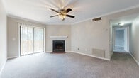 This single-floor residence offers a well-organized layout across two bedrooms and two full bathrooms. The living room serves as the focal point of the home, featuring a wood-burning fireplace with a white mantel, a ceiling fan with light fixture, elegant crown molding, and sliding glass doors that open to an outdoor balcony, allowing ample natural light into the space. Neutral-toned carpet and warm beige walls create a cohesive, inviting atmosphere throughout.

Adjacent to the living room, a dedicated dining area is accented with a pendant chandelier and additional crown molding, providing a defined space for meals. The galley-style kitchen is efficiently designed with white cabinetry, laminate countertops, wood-look flooring, and black appliances including a range and refrigerator.

The primary bedroom is generously proportioned, featuring plush carpet, a ceiling fan, a walk-in closet, and a private en-suite bathroom complete with a single-sink vanity and a tub-shower combination. The second bedroom offers comfortable carpet flooring, a natural light window, and a reach-in closet with built-in shelving. A second full bathroom mirrors the first in design, maintaining consistency throughout the home.