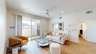 Located in Lathrop, CA, this thoughtfully designed single-story home offers a clean, contemporary aesthetic throughout. The living room serves as the heart of the space, featuring warm light wood-style flooring, recessed lighting, a ceiling fan, and large sliding glass doors that open to an outdoor patio, filling the room with natural light and providing seamless indoor-outdoor connectivity. The kitchen is outfitted with high-gloss white cabinetry, stainless steel appliances including a refrigerator, range, and microwave, and light countertops that reinforce the home's bright, modern character. A compact dining nook adjacent to the kitchen features a round marble-top table beneath a statement pendant light. The primary bedroom is serene and airy, with a ceiling fan, wide window with outdoor views, and light wood flooring. A second bedroom comfortably accommodates twin beds and benefits from generous natural light through a large window. The home includes two bathrooms: one full bath with a subway-tiled tub-shower combination, and a second bath featuring an extended white vanity with an illuminated mirror. Consistent light wood flooring and a neutral white palette unify the entire home, creating a calm and cohesive atmosphere throughout.