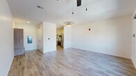 Located at 617 E Second St in Dayton, Ohio, this single-floor unit offers a thoughtfully designed layout that maximizes its compact footprint. The interior features consistent wood-look plank flooring throughout the main living areas, lending warmth and visual continuity across the space.

The open-concept kitchen and living area form the heart of the unit. The kitchen is outfitted with stainless steel appliances, including a French door refrigerator, electric range, and over-the-range microwave. Two-tone cabinetry pairs cream upper cabinets with wood-grain lower cabinets, accented by gold hardware. A textured tile backsplash and light quartz countertops complete the polished look. A gold-finish faucet adds a refined detail to the undermount sink.

The living area is bright and open, benefiting from a window with urban views and a ceiling fan with integrated lighting. Crisp white walls provide a clean, neutral backdrop throughout.

The bathroom is finished to a high standard, featuring large-format marble-look tile flooring, a glass-enclosed walk-in shower with white subway tile and gold fixtures, a wood-grain vanity, and built-in open shelving for storage. A distinctive blue entry door adds a modern, welcoming touch to the overall design.