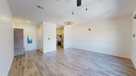 Located at 617 E Second St in Dayton, Ohio, this single-floor unit offers a thoughtfully designed layout that maximizes its compact footprint. The interior features consistent wood-look plank flooring throughout the main living areas, lending warmth and visual continuity across the space.

The open-concept kitchen and living area form the heart of the unit. The kitchen is outfitted with stainless steel appliances, including a French door refrigerator, electric range, and over-the-range microwave. Two-tone cabinetry pairs cream upper cabinets with wood-grain lower cabinets, accented by gold hardware. A textured tile backsplash and light quartz countertops complete the polished look. A gold-finish faucet adds a refined detail to the undermount sink.

The living area is bright and open, benefiting from a window with urban views and a ceiling fan with integrated lighting. Crisp white walls provide a clean, neutral backdrop throughout.

The bathroom is finished to a high standard, featuring large-format marble-look tile flooring, a glass-enclosed walk-in shower with white subway tile and gold fixtures, a wood-grain vanity, and built-in open shelving for storage. A distinctive blue entry door adds a modern, welcoming touch to the overall design.