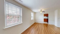 Located at 1414 Newell Rd in Richmond, Virginia, this two-bedroom, one-bathroom single-story home offers a practical and comfortable layout. The living room serves as the central gathering space, featuring warm hardwood-style flooring, a ceiling fan with light fixture, and multiple windows that invite natural light and outdoor views. The open sightline connects the living area directly to the kitchen, enhancing the sense of flow throughout the home. The kitchen is well-equipped with warm honey-toned wood cabinetry, a gas range, dishwasher, and full-size refrigerator, all finished in black. Tile flooring and a bright window overlooking greenery complete the kitchen's functional design. Both bedrooms are carpeted for comfort and include windows with natural light. The spacious primary bedroom offers generous floor area and direct access to the hallway. The secondary bedroom features a closet and an additional window. The bathroom is clean and straightforward, with a tiled tub-shower combination and a decorative shower curtain. Throughout the home, neutral white walls and clean finishes create a bright, move-in-ready atmosphere suited for comfortable everyday living.