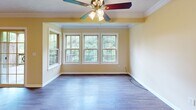 Located in Seven Fields, PA, this two-bedroom, two-bathroom residence offers a thoughtfully organized single-floor layout designed for comfortable everyday living. The combined kitchen and living area serves as the heart of the home, where the kitchen features warm honey-toned oak cabinetry, granite-look countertops, stainless steel appliances including a refrigerator and range, recessed lighting, and durable hardwood-style flooring. A pass-through counter connects the kitchen to the living space, which is bathed in natural light from a bank of large windows overlooking lush greenery, complemented by a ceiling fan and crown molding details. Both bedrooms are generously proportioned, each outfitted with plush carpeting, ceiling fans with light fixtures, and ample natural light from well-positioned windows. The primary bedroom includes a closet and comfortable square footage for a full furniture arrangement. The bathrooms are finished with wood-toned vanity cabinetry, white countertops, wall-mounted medicine cabinets, and hardwood-style flooring. Additional utility space features a unique angled ceiling, adding architectural character. The warm, neutral color palette throughout creates a cohesive and inviting ambiance across the entire residence.