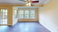 Located in Seven Fields, PA, this two-bedroom, two-bathroom residence offers a thoughtfully organized single-floor layout designed for comfortable everyday living. The combined kitchen and living area serves as the heart of the home, where the kitchen features warm honey-toned oak cabinetry, granite-look countertops, stainless steel appliances including a refrigerator and range, recessed lighting, and durable hardwood-style flooring. A pass-through counter connects the kitchen to the living space, which is bathed in natural light from a bank of large windows overlooking lush greenery, complemented by a ceiling fan and crown molding details. Both bedrooms are generously proportioned, each outfitted with plush carpeting, ceiling fans with light fixtures, and ample natural light from well-positioned windows. The primary bedroom includes a closet and comfortable square footage for a full furniture arrangement. The bathrooms are finished with wood-toned vanity cabinetry, white countertops, wall-mounted medicine cabinets, and hardwood-style flooring. Additional utility space features a unique angled ceiling, adding architectural character. The warm, neutral color palette throughout creates a cohesive and inviting ambiance across the entire residence.