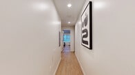 Located at 1427 Barry Ave in the desirable West Los Angeles neighborhood of 90025, this thoughtfully designed unit offers three bedrooms and three bathrooms within a smartly optimized single-floor layout. Light wood-tone flooring runs throughout, creating a warm and cohesive aesthetic that ties the space together.

A clean, well-lit hallway serves as the central corridor connecting the rooms, accented with recessed lighting and contemporary wall art. Each bedroom is efficiently arranged, featuring built-in wood-grain cabinetry and closets that maximize storage without sacrificing style. The primary bedroom offers a comfortable footprint with direct access to built-in shelving and views into a dedicated kitchen area equipped with matching wood cabinetry.

All three bathrooms are finished to a high standard, featuring large-format porcelain tile flooring, glass-enclosed walk-in showers, and clean white walls. One bathroom showcases marble-look tile with a wood vanity topped by a white quartz countertop, adding a refined touch. The additional bathrooms maintain the same modern, minimalist aesthetic with sleek chrome fixtures.

A dedicated laundry area and a central kitchen round out the functional layout. Throughout the unit, recessed lighting, neutral tones, and quality finishes create a clean, contemporary environment well-suited for efficient urban living in Los Angeles.