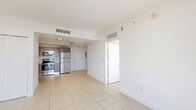 Located at 1900 SW 8th St in Miami's vibrant Little Havana neighborhood, this one-bedroom, one-bathroom unit offers a well-designed layout across a single floor. Large-format tile flooring runs throughout, giving the space a clean, cohesive look.

The open-plan living and dining area is bright and airy, benefiting from abundant natural light and direct access to a private balcony through floor-to-ceiling sliding glass doors, which frame elevated views of the Miami skyline and surrounding greenery.

The kitchen is efficiently designed with warm wood-toned cabinetry, a tile backsplash, light countertops, and a full suite of stainless steel appliances including a refrigerator, range, microwave, and dishwasher. Track lighting above the kitchen transition adds both function and style.

The bedroom is a comfortable, sunlit retreat with a large window showcasing sweeping city and treetop views. Three closets provide generous storage throughout the unit, a notable feature for a space of this scale.

The bathroom is finished in clean white tile and includes a full soaking tub with shower. A dedicated entrance foyer and hallway round out the layout, adding a sense of arrival and separation between living spaces. The overall aesthetic is contemporary and minimal.