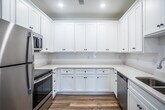 This single-story residence at The Burgundy in Jonesboro, Arkansas offers a clean, modern interior designed for comfortable everyday living. Warm wood-look luxury vinyl flooring runs consistently throughout the unit, creating a cohesive and low-maintenance foundation across all rooms.

The kitchen is a standout feature, finished with crisp white shaker-style cabinetry that extends to the ceiling for generous storage capacity. Light countertops complement the white palette, while stainless steel appliances—including a refrigerator and dishwasher—add a modern, polished touch. Recessed lighting illuminates the space efficiently.

Both bedrooms are well-proportioned, each featuring a ceiling fan with integrated lighting and a window that allows natural light to fill the room. The rooms offer a bright, neutral backdrop suitable for a variety of furniture arrangements.

The full bathroom is finished cleanly with a white tub-shower surround, chrome fixtures, and a curved shower rod, alongside a vanity and wood-look flooring that ties into the rest of the unit.

One bedroom includes access to an in-unit laundry area with washer and dryer hookups, adding notable convenience. Throughout the unit, white walls and natural light from multiple windows contribute to a fresh, airy ambiance.