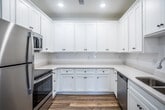 This single-story residence at The Burgundy in Jonesboro, Arkansas offers a clean, modern interior designed for comfortable everyday living. Warm wood-look luxury vinyl flooring runs consistently throughout the unit, creating a cohesive and low-maintenance foundation across all rooms.

The kitchen is a standout feature, finished with crisp white shaker-style cabinetry that extends to the ceiling for generous storage capacity. Light countertops complement the white palette, while stainless steel appliances—including a refrigerator and dishwasher—add a modern, polished touch. Recessed lighting illuminates the space efficiently.

Both bedrooms are well-proportioned, each featuring a ceiling fan with integrated lighting and a window that allows natural light to fill the room. The rooms offer a bright, neutral backdrop suitable for a variety of furniture arrangements.

The full bathroom is finished cleanly with a white tub-shower surround, chrome fixtures, and a curved shower rod, alongside a vanity and wood-look flooring that ties into the rest of the unit.

One bedroom includes access to an in-unit laundry area with washer and dryer hookups, adding notable convenience. Throughout the unit, white walls and natural light from multiple windows contribute to a fresh, airy ambiance.