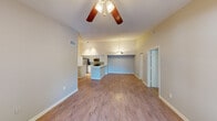 This single-floor residence offers a thoughtfully designed open-concept layout that seamlessly connects the living, dining, and kitchen areas. The main living space features vaulted ceilings, hardwood-style flooring, and a ceiling fan, creating an airy and comfortable atmosphere. A sliding glass door opens to a private balcony with outdoor views, flooding the room with natural light.

The kitchen is a functional highlight, outfitted with stainless steel appliances including a refrigerator, electric range, microwave, and dishwasher. Crisp white cabinetry, stone-look countertops, a mosaic tile backsplash, and a central island with a built-in sink provide both style and practicality. Track lighting and a pendant fixture illuminate the workspace effectively.

The bedrooms are carpeted for comfort and are generously proportioned, with one featuring direct access to a well-lit bathroom equipped with a walk-in shower, vanity with stone countertop, and tile flooring. A dedicated walk-in closet with built-in wire shelving offers abundant storage. A separate laundry area with in-unit washer hookups adds everyday convenience. Throughout, the neutral color palette and clean finishes contribute to a bright, move-in-ready environment.
