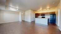 This single-floor residence offers a thoughtfully designed open-concept layout that seamlessly connects the living area and kitchen. Rich hardwood-style flooring flows consistently throughout the entire space, providing a warm and cohesive aesthetic. The expansive living area is bathed in natural light through multiple windows fitted with blinds, creating a bright and welcoming atmosphere.

The kitchen is a functional centerpiece, featuring rich dark wood cabinetry that extends to the ceiling for generous storage, a granite-style countertop peninsula with an integrated sink, and a full suite of black appliances including a gas range, over-range microwave, and refrigerator. Track lighting illuminates both the kitchen and living areas with precision.

The bedrooms are generously proportioned, each offering hardwood-style flooring, neutral wall tones, and windows that invite natural light. The primary suite includes access to a well-sized walk-in closet outfitted with wire shelving systems for organized storage.

The bathroom is clean and practical, featuring dark wood vanity cabinetry, a white countertop with an integrated sink, and a full tub-shower combination with tiled surround. Throughout the space, neutral tones and consistent finishes create a cohesive, move-in ready environment suitable for a variety of living arrangements.