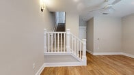Located at 17014 Fairmount Way in Pineville, NC, this well-appointed three-story home offers 2 bedrooms and 3 bathrooms across a thoughtfully designed layout. The entry level provides a welcoming foundation with a staircase featuring elegant white-painted railings and warm hardwood-style flooring that flows throughout the main living areas.

The main floor is the heart of the home, showcasing an open-concept living, dining, and kitchen space. The kitchen stands out with tall white shaker cabinets reaching to the ceiling, a classic subway tile backsplash, stainless steel appliances, and a central island with a white quartz countertop and undermount sink. Pendant lighting and French doors with transom windows flood the space with natural light.

A convenient half bathroom on this level features a stylish pedestal sink, a framed mirror, and matching hardwood-style flooring. Crown molding accents the dining area, which is illuminated by a contemporary drum pendant light.

The upper floor houses both bedrooms, each filled with natural light from multiple windows with white plantation blinds. The bedrooms feature plush carpet and crown molding. The spacious primary bedroom includes an en suite bathroom appointed with a double-sink vanity, white cabinetry with dark hardware, quartz countertops, tile flooring, and a glass-enclosed shower.