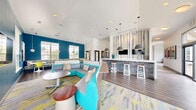 Located at 2053 Willowbrook Dr in West Lafayette, Indiana, this dynamic community clubhouse delivers a bold, contemporary design across a spacious single-floor layout. The interior is defined by a lively, curated color palette — vivid teal accent walls, chartreuse seating, and multicolored patterned textiles — creating an energetic yet cohesive atmosphere throughout.

The primary living area features soaring ceilings, recessed lighting, and rich wood-plank flooring, anchored by a large sectional sofa in turquoise and complemented by abstract area rugs. A built-in bar counter with pendant lighting and mounted flat-screen TVs adds a social hub feel, while striped decorative drapery panels lend vertical drama to the space. A cozy dining nook nearby offers built-in banquette seating, white pedestal tables, and bright yellow chairs bathed in natural light from oversized gridded windows.

A second living area showcases large-format tile flooring, bold pop-art wall pieces, and a central oval dining table surrounded by teal chairs — an ideal gathering space with strong visual character.

The dedicated office suite includes a computer workstation with individual stations separated by privacy dividers, a vibrant geometric accent wall, and an adjoining conference room equipped with a large display screen, a whiteboard, and a full-glass pivot door — providing a functional, well-equipped workspace.