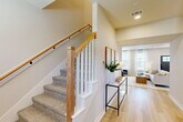 Located in College Station, TX, this two-story home offers a thoughtfully designed layout spread across two floors. The main level provides the majority of the living space, featuring an open-concept arrangement that seamlessly connects the living room, dining area, and kitchen. The living room is highlighted by a striking board-and-batten accent wall, light hardwood-style flooring, and large windows that fill the space with natural light. The kitchen is well-appointed with dark cabinetry, stainless steel appliances, a gas range, and a central island with a white quartz countertop and seating for multiple guests, complemented by an industrial-style pendant light fixture. A pantry and dedicated entrance add everyday convenience on this level. Upstairs, the primary bedroom features plush carpet, a ceiling fan, natural light from a corner window, and direct access to both a closet and the full bathroom. The bathroom includes a tub/shower combo with matte black fixtures and light wood-style tile flooring. A flexible secondary room on the upper floor is well-suited as a home office or study, featuring dual windows and ceiling fan. The staircase, with its warm wood railing and white balusters, serves as an elegant architectural focal point connecting both levels.