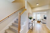Located in College Station, TX, this two-story home offers a thoughtfully designed layout spread across two floors. The main level provides the majority of the living space, featuring an open-concept arrangement that seamlessly connects the living room, dining area, and kitchen. The living room is highlighted by a striking board-and-batten accent wall, light hardwood-style flooring, and large windows that fill the space with natural light. The kitchen is well-appointed with dark cabinetry, stainless steel appliances, a gas range, and a central island with a white quartz countertop and seating for multiple guests, complemented by an industrial-style pendant light fixture. A pantry and dedicated entrance add everyday convenience on this level. Upstairs, the primary bedroom features plush carpet, a ceiling fan, natural light from a corner window, and direct access to both a closet and the full bathroom. The bathroom includes a tub/shower combo with matte black fixtures and light wood-style tile flooring. A flexible secondary room on the upper floor is well-suited as a home office or study, featuring dual windows and ceiling fan. The staircase, with its warm wood railing and white balusters, serves as an elegant architectural focal point connecting both levels.
