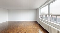 This three-bedroom, one-bathroom unit at 18-20 Skipton Court offers a well-distributed single-floor layout in Toronto's northwest end. The interior is characterized by warm, richly patterned parquet flooring that runs throughout the living areas and all three bedrooms, lending the space a classic, timeless aesthetic complemented by clean white walls.

The galley-style kitchen has been updated with white shaker cabinetry, grey tile backsplash, light-toned countertops, and a full suite of stainless steel appliances including a range, over-the-range microwave, and refrigerator. Light tile flooring and a flush ceiling fixture complete the functional space.

Each bedroom is a well-proportioned room featuring the same parquet flooring, white panel closet doors providing built-in storage, and large windows that admit natural light. Radiator heating units are present in several rooms, consistent with the building's classic construction. The primary bedroom offers a comfortable footprint suitable for a full furniture arrangement.

The bathroom is finished with white subway tile surrounding a soaker tub and shower combination, paired with a pedestal sink and mirror. Windows throughout the unit frame views of a natural, wooded landscape to the rear of the property.