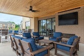 This generously sized single-floor amenity space offers a well-appointed and thoughtfully designed environment spanning over 2,000 square feet. The open-concept layout is unified by warm hardwood-style flooring and striking exposed wood ceiling beams that lend a modern-rustic character throughout.

The central gathering area features a large communal kitchen with an expansive white quartz island, bar seating for multiple guests, white shaker cabinetry, a stainless steel refrigerator, a wall oven, a mosaic tile backsplash, and pendant lighting. This area transitions seamlessly into a comfortable lounge, where a tile-surround fireplace serves as a focal point beneath a mounted flat-screen TV. Floor-to-ceiling windows and glass doors flood the lounge with natural light and provide direct views and access to an outdoor terrace with seating.

A dedicated seating nook with accent chairs offers additional views to the exterior through large windows. The fitness center is well-equipped with cardio machines including treadmills, ellipticals, and a rowing machine, as well as free weights, resistance equipment, a ceiling fan, full-wall mirrors, and a wall-mounted TV. The overall ambiance throughout is clean, modern, and inviting, designed to support both social gatherings and individual wellness.