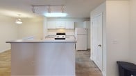 This single-floor unit is thoughtfully laid out to maximize functionality across its living spaces. The open-concept kitchen and living area serves as the heart of the unit, featuring wood-look plank flooring, a textured ceiling, and a peninsula counter that defines the kitchen zone while maintaining visual connectivity to the broader living space. The kitchen is well-equipped with white cabinetry, light countertops, a coil-top range, a dishwasher, and a full-size refrigerator. Track lighting and a built-in ceiling fixture provide ample illumination. A sliding door with vertical blinds in the living area introduces natural light and exterior access.

The bedrooms are carpeted and offer a comfortable, quiet atmosphere. Each room benefits from natural light through blinds-fitted windows. At least one bedroom includes a walk-in closet with built-in shelving, while another features direct access to an adjoining bathroom. Two full bathrooms serve the unit; one includes a vanity with white cabinetry, a large mirror, and wood-look flooring, while the other offers a full soaking tub and shower combination alongside a similarly styled vanity. Throughout, neutral tones and clean white trim create a cohesive, move-in ready aesthetic.