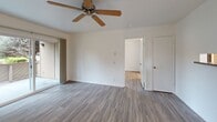 Located at 955 Escalon Ave in Sunnyvale, California, this one-bedroom, one-bathroom residence offers a well-organized, efficient layout with consistent light-toned hardwood-style flooring running throughout the entire space. The combined kitchen and living area forms the heart of the home, where a galley-style kitchen is outfitted with warm oak cabinetry, granite-style countertops, stainless steel appliances including a dishwasher and refrigerator, and a skylight that bathes the space in natural light. A pass-through window connects the kitchen to the adjacent living area, enhancing the open feel. The living room is bright and airy, featuring a ceiling fan, a baseboard heater, and a sliding glass door that opens to a private outdoor balcony with greenery views. The bedroom is a comfortable and well-proportioned room with a window overlooking lush landscaping, a wall-unit climate controller, and easy access to the rest of the unit. The bathroom is clean and functional, appointed with a wood-framed vanity, granite-style countertop, a large mirror, and wood-look tile flooring. A staircase is also included within the unit. The overall ambiance is clean, neutral, and move-in ready, well-suited for comfortable living in the heart of Silicon Valley.