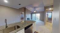 This single-floor residence offers a thoughtfully designed open-concept layout that seamlessly connects the kitchen and living areas. The kitchen is a standout feature, showcasing granite countertops, white shaker cabinetry, a stainless steel dishwasher, refrigerator, range, and built-in microwave, all complemented by a tile backsplash and rich hardwood-style flooring. A central island with an undermount sink adds both functionality and visual appeal.

The open living area flows naturally from the kitchen and is highlighted by vaulted ceilings with crown molding, a ceiling fan, and a classic tiled fireplace. Vertical blinds frame a sliding door that leads to a private balcony, offering natural light and outdoor views. Plush carpeting throughout the living spaces and bedrooms adds warmth and comfort.

The bedrooms are generously sized, each equipped with a ceiling fan and ample natural light from well-placed windows. The bathrooms continue the home's refined aesthetic with granite vanity tops, white cabinetry, large mirrors, and tiled tub-shower combinations set on hardwood-style flooring. The overall ambiance is clean, modern, and move-in ready, with neutral tones and consistent finishes throughout.