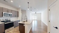 Located on Autumn Field Dr in Huntersville, NC, this well-appointed 2-bedroom, 2-bathroom home offers a thoughtfully designed single-level layout with modern finishes throughout. The open-concept kitchen and living area serves as the heart of the home, featuring a large island with a quartz countertop and matte black pull-down faucet, rich wood-toned cabinetry, a white subway tile backsplash, and a full suite of stainless steel appliances. Pendant lighting over the island and recessed ceiling lights add warmth and functionality to the space. The living room extends naturally from the kitchen, bathed in natural light from a set of glass panel doors that lead to an outdoor area. A ceiling fan overhead completes the comfortable, airy atmosphere. Both bedrooms offer generous proportions with wood-look flooring and ceiling fans, providing a calm and neutral retreat. The primary bedroom includes access to a dedicated closet. The two bathrooms are finished with wood-toned vanities, quartz countertops, and matte black hardware. One bathroom features a walk-in glass-door shower, while the other includes a window for natural light. Consistent wood-look flooring flows throughout the entire home, tying together the clean, contemporary aesthetic from room to room.